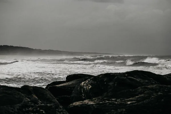 Paysage d'un plan d'eau rugueux avec des vagues éclaboussant le rivage rocheux — Photo