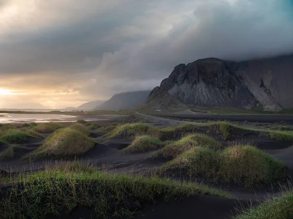 Krajobraz ujęcia trawiastych wzgórz na plaży z szarą górą w oddali — Zdjęcie stockowe