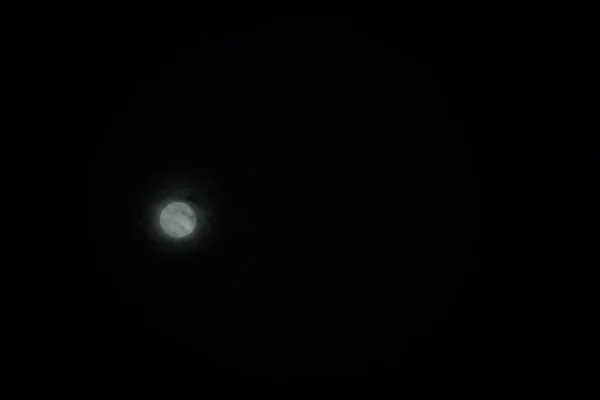 Ciemne ujęcie nocnego nieba z księżycem świecącym przez chmury — Zdjęcie stockowe