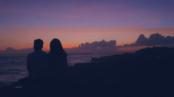 海を見ている男と女のシルエットで夕日の間に海を撮影水平方向 — ストック写真