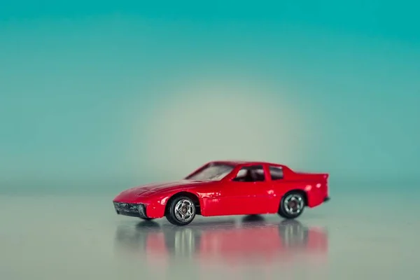 Знімок декоративного червоного іграшкового автомобіля з відзеркаленням і на світло - синьому фоні. — стокове фото