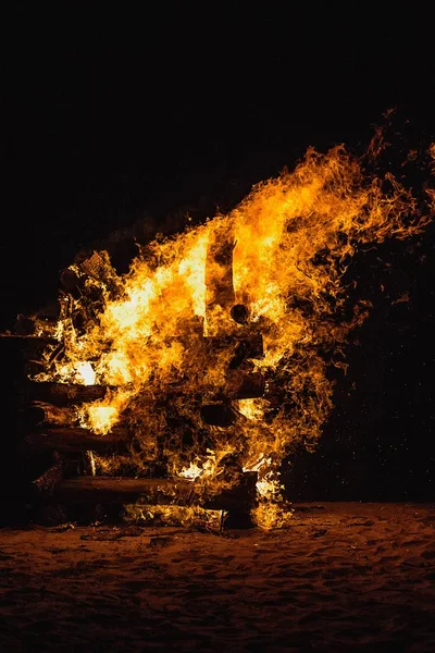 Tiro vertical de queima de madeira empilhada durante a noite — Fotografia de Stock