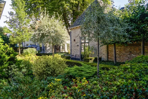 Mooi stenen huis omringd door bomen, groene planten en bloemen in een tuin — Stockfoto