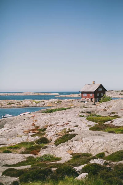 Isolada casa de madeira vermelha na costa perto do oceano sob o céu azul em um dia ensolarado — Fotografia de Stock