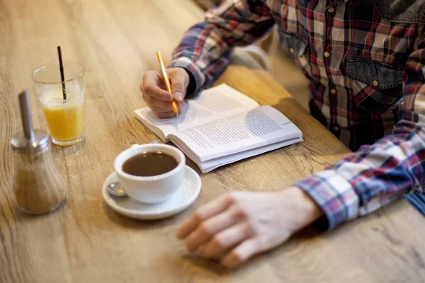 High angle shot of a male readin a book with coffee and a juice on the table — Stock Photo, Image