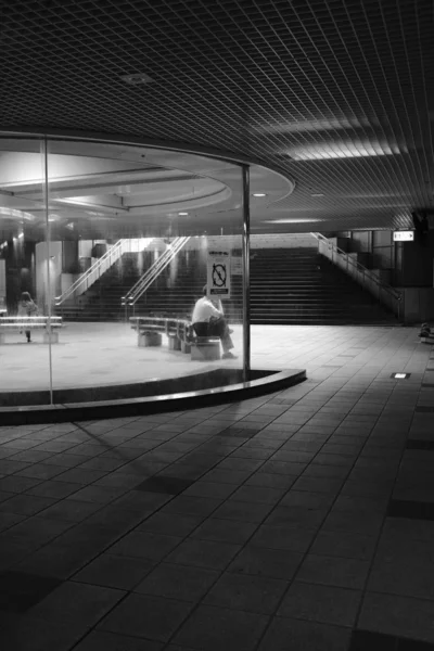 Grayscale tiro do interior de um edifício com escadas e uma pessoa sentada no banco — Fotografia de Stock