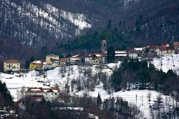 Gyönyörű kép épületek a havas dombon erdős hegyek a háttérben — Stock Fotó
