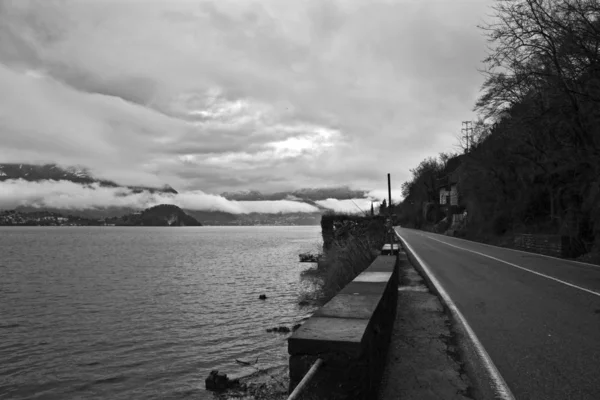 Estrada vazia perto do mar sob um céu nublado em preto e branco — Fotografia de Stock