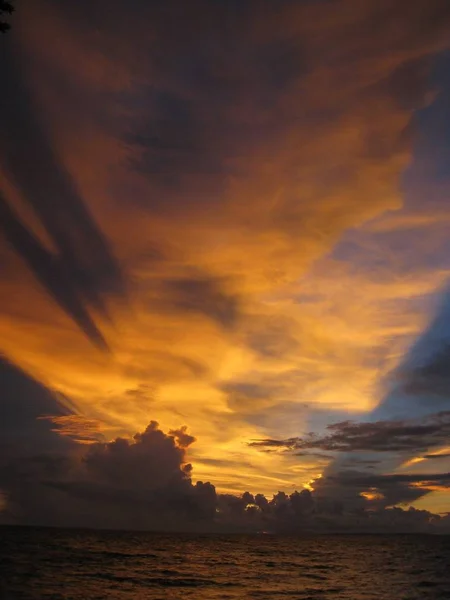 Vertical shot of the sea under a cloudy sky during sunset