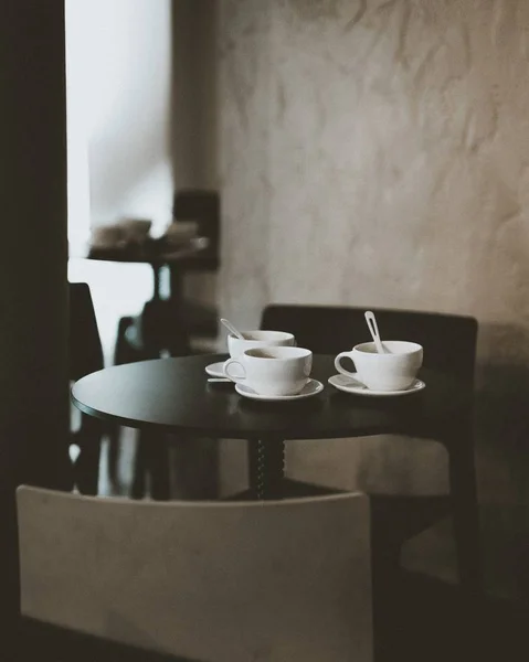 Vertical shot of coffee cups on a table with a blurred background — ストック写真