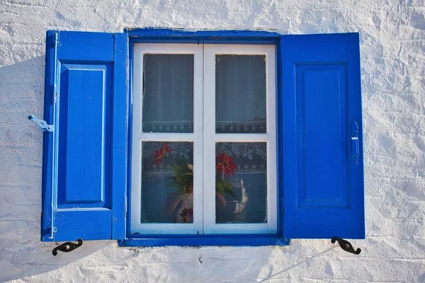 Primer plano de una ventana azul de madera abierta con una flor en una maceta durante el día en Symi, Grecia — Foto de Stock