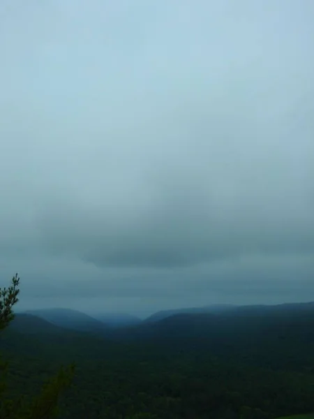 Κατακόρυφη λήψη πράσινων βουνών και ενός πεδίου καλυμμένου με ομίχλη νωρίς το πρωί — Φωτογραφία Αρχείου