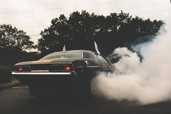Svart coupe bil på en väg täckt av rök omgiven av träd — Stockfoto