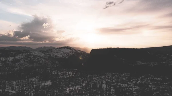 Bred bild av berg omgiven av träd täckta av snö under en lila himmel — Stockfoto