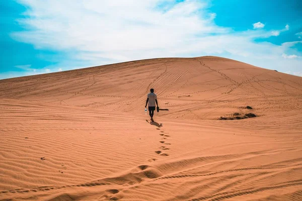 Ampia ripresa di una persona che cammina su una sabbia desertica sotto un cielo blu — Foto Stock