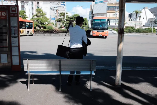 Οριζόντια λήψη αρσενικού σε σταθμό λεωφορείων που περιμένει το λεωφορείο κατά τη διάρκεια της ημέρας — Φωτογραφία Αρχείου