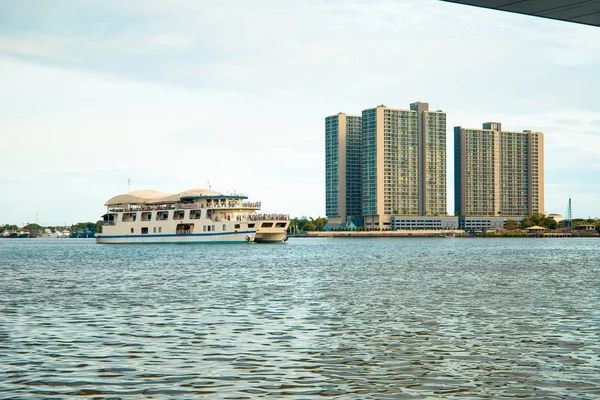 Tiro largo de um barco branco no corpo de água cercado y edifícios altos sob um céu limpo — Fotografia de Stock
