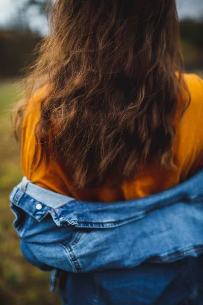 Tiro de close-up seletivo de uma jovem fêmea com cabelo longo e uma jaqueta jean — Fotografia de Stock