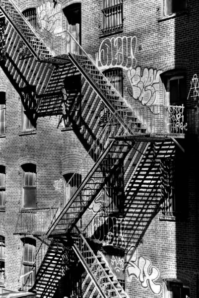 Escalera vertical a escala de grises de escaleras de metal cerca de un antiguo edificio con ventanas — Foto de Stock