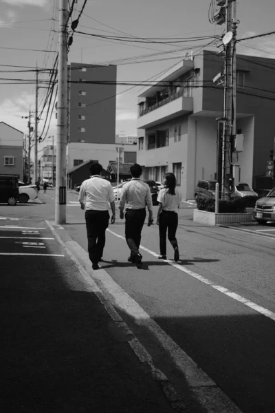 Κατακόρυφη φωτογραφία τριών φίλων που περπατούν στο δρόμο κατά τη διάρκεια της ημέρας. — Φωτογραφία Αρχείου