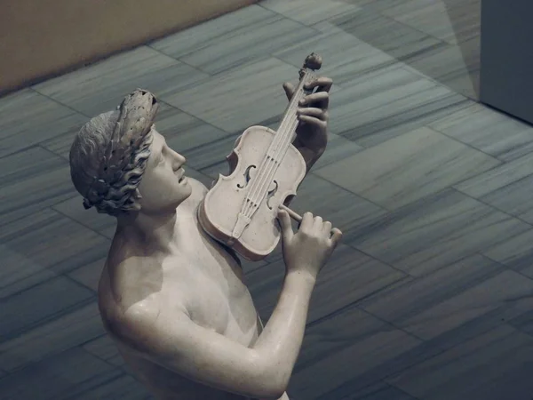 Wysoki kąt ujęcia szarego posągu samca grającego na skrzypcach — Zdjęcie stockowe