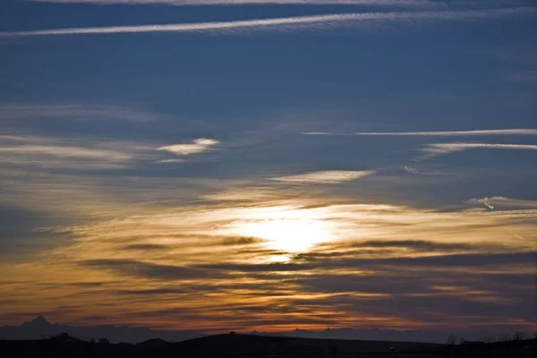 Silhouette of hills under a blue and yellow cloudy sky — Stock Photo, Image