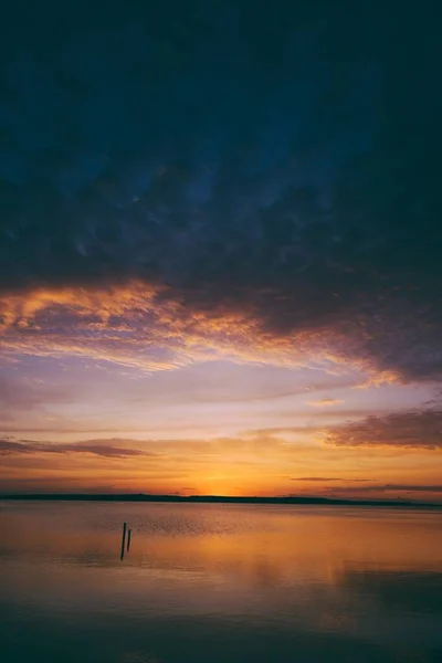 Tiro vertical de un mar bajo un cielo nublado al atardecer — Foto de Stock