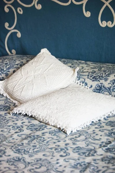 Vertical shot of white pillows on a bed with blue and white patterned sheets — Stock Photo, Image