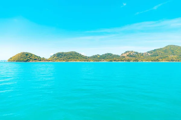 Amplo tiro de colinas cobertas de verde por um mar azul claro sob um céu azul — Fotografia de Stock