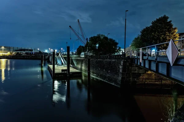 Pont en béton sur l'eau avec beaucoup de lumières sous le ciel bleu la nuit — Photo