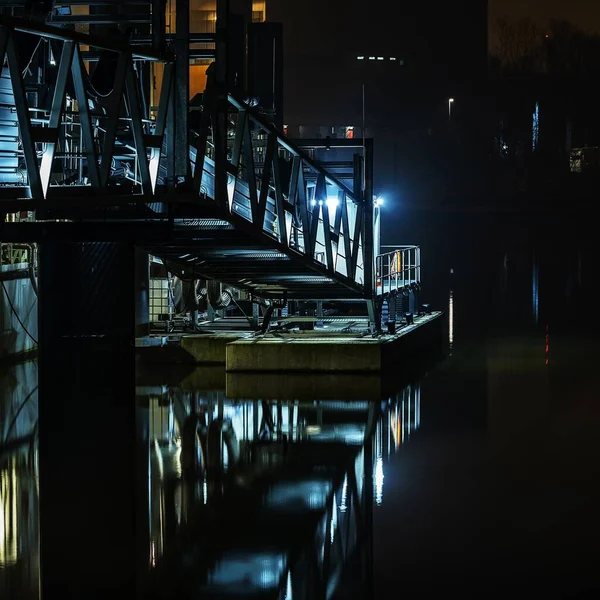 Disparo vertical de escaleras metálicas con luces cerca del agua durante la noche — Foto de Stock