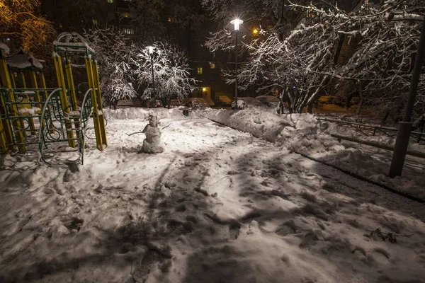 Colpo orizzontale di un parco giochi in un parco vicino a un complesso residenziale coperto di neve a Mosca — Foto Stock