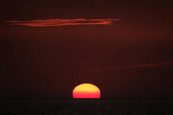 Belo tiro do sol que se põe em um céu vermelho — Fotografia de Stock