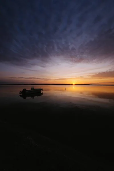 Vertical shot of a boat on the water under a dark cloudy sky — Stock Photo, Image