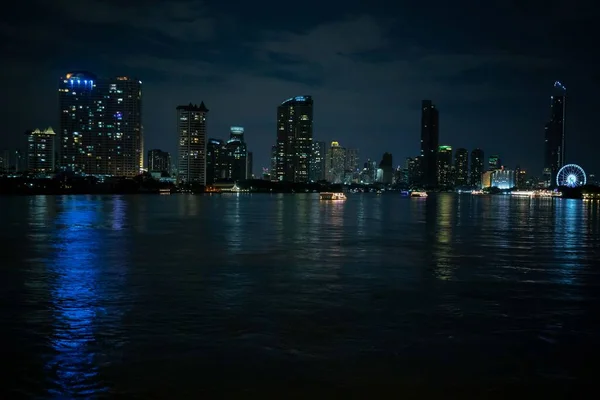 Mooie brede shot van verlichte wolkenkrabbers door het lichaam van het water in een stad tijdens de nacht — Stockfoto