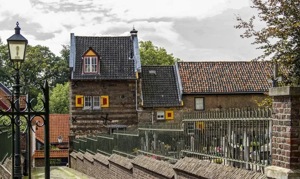 Colpo orizzontale di un edificio marrone con tetto nero e marrone circondato da recinzione verde — Foto Stock