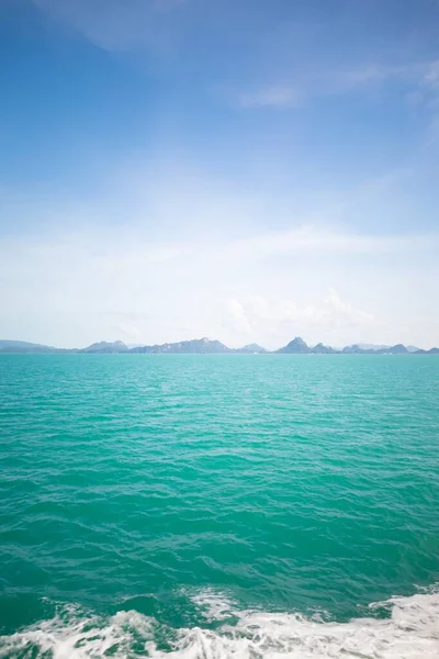 Tiro vertical de mar azul claro abaixo de um céu azul — Fotografia de Stock