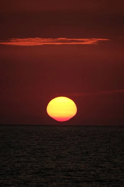 Vertikala skott av solen går ner i en röd himmel — Stockfoto