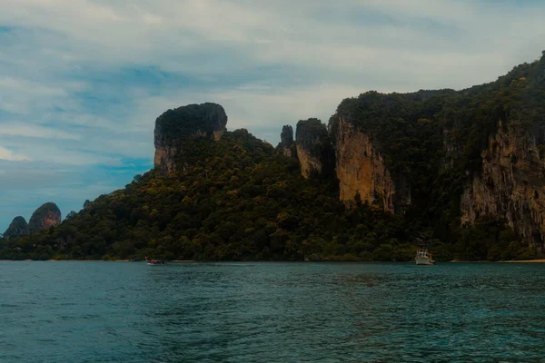 Amplio plano de acantilados cubiertos de verde por el mar bajo un cielo azul — Foto de Stock