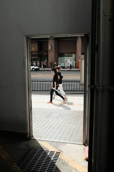 Κάθετη λήψη ενός άνδρα και μιας γυναίκας που φορούν μαύρα πουκάμισα περπατώντας σε ένα πεζοδρόμιο στο δρόμο — Φωτογραφία Αρχείου