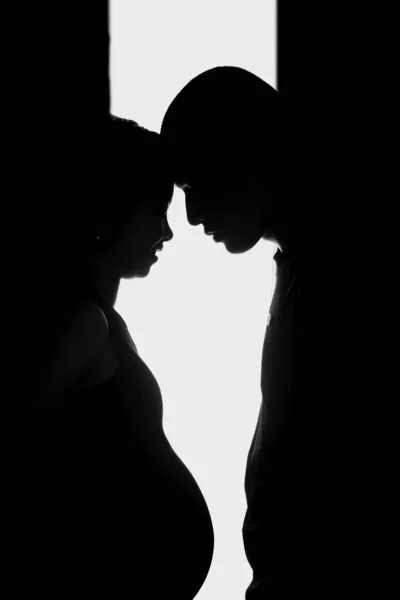 Vertical silhouette shot of a pregnant woman and a man with their foreheads against each other — Stock Photo, Image