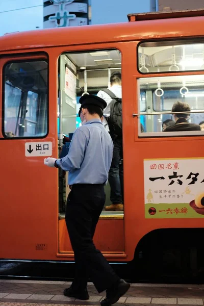 オレンジのバスの近くに立つ青いシャツと黒いパンツを着た男性の垂直ショット — ストック写真