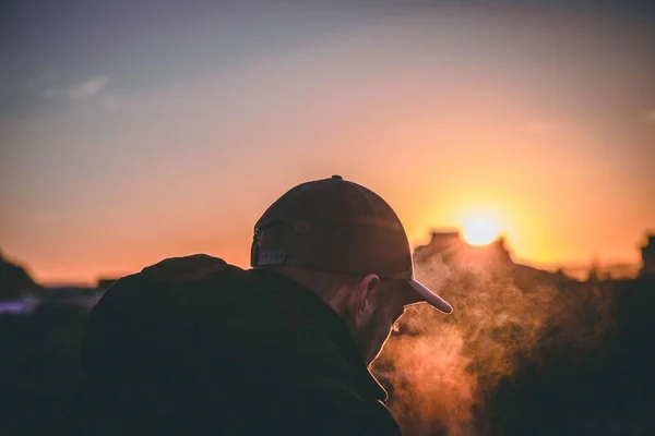 Plan peu profond du dos d'un homme portant une casquette pendant l'heure dorée du coucher du soleil. — Photo