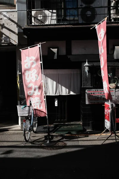 Вертикальний постріл велосипеда з кошиком, припаркований біля будинку з червоними знаками біля входу. — стокове фото