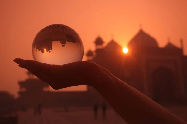 Silueta osoby držící skleněnou kouli s odrazem Taj Mahal v Indii při západu slunce — Stock fotografie