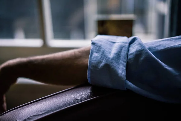 파란색 셔츠 소매와 함께 안락 의자에 누워 있는 사람의 팔을 클로즈업 사진 — 스톡 사진