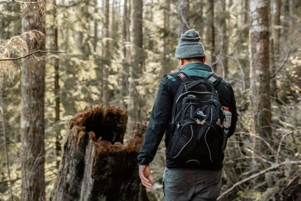 Blízký záběr muže s batohem kráčejícího s rozmazaným lesem v pozadí — Stock fotografie