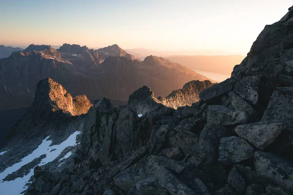Tiro horizontal de montanhas rochosas cobertas de neve durante o nascer do sol — Fotografia de Stock