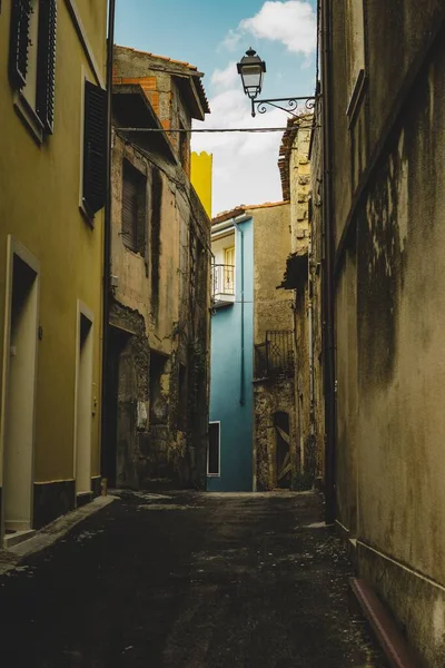 Tiro vertical de un callejón vacío alineado con viejos edificios amarillos que conducen a un edificio azul — Foto de Stock