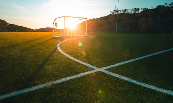 Szerokie ujęcie boiska piłkarskiego z promieniami słońca pod pięknym zachmurzonym niebem — Zdjęcie stockowe